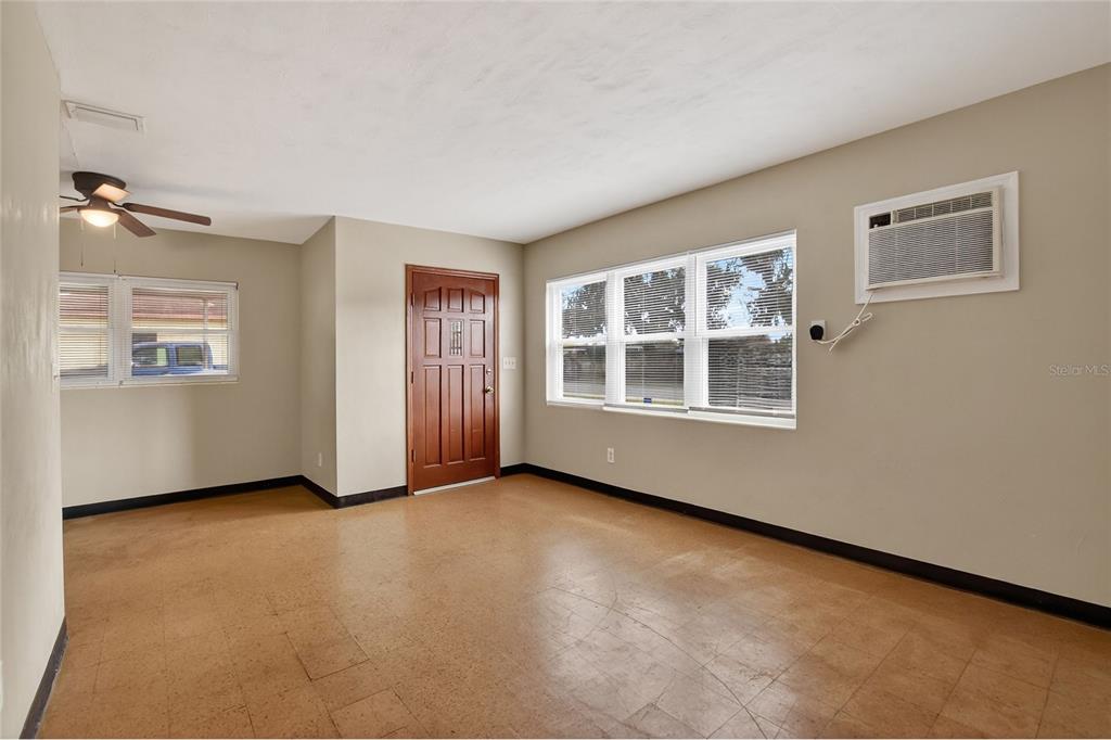 An empty room features tan walls, a brown door, windows, and a tiled floor — 1248 WOODLAND AVENUE, LAKELAND, FL
