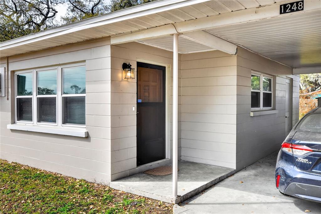 The exterior of a single-story house features a concrete block facade and a covered carport — 1248 WOODLAND AVENUE, LAKELAND, FL