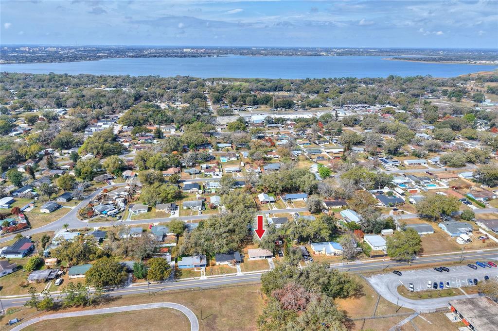 An aerial view shows a single-story house marked by a red arrow in a neighborhood — 1248 WOODLAND AVENUE, LAKELAND, FL