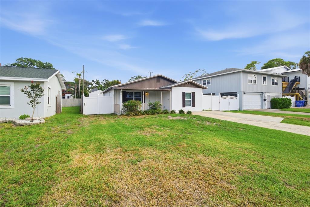 A single-story house with a brown roof and white siding sits behind a grassy yard — 1842 SHORE ACRES BOULEVARD NE, ST PETERSBURG, FL
