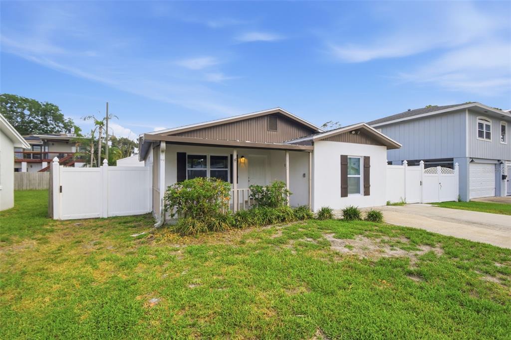 A single-story house with a white exterior, brown gable roof, and a front porch — 1842 SHORE ACRES BOULEVARD NE, ST PETERSBURG, FL