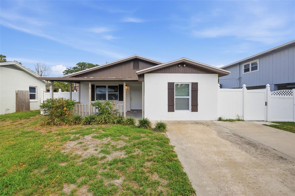 A single-story house with a white stucco facade, brown trim, and a front porch — 1842 SHORE ACRES BOULEVARD NE, ST PETERSBURG, FL