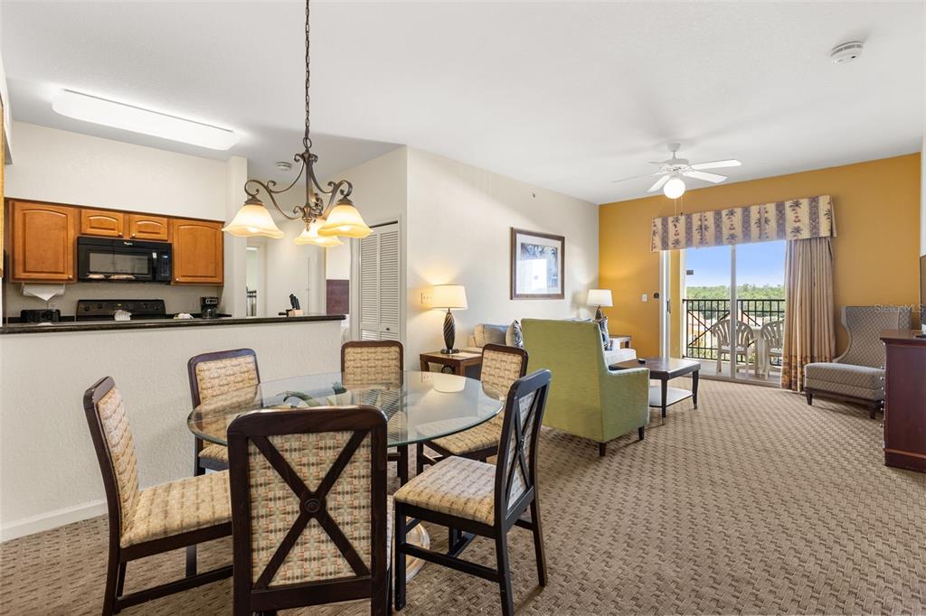 A dining area with a glass table sits before a living room and a balcony — 8100 POINCIANA BOULEVARD UNIT 2505, ORLANDO, FL