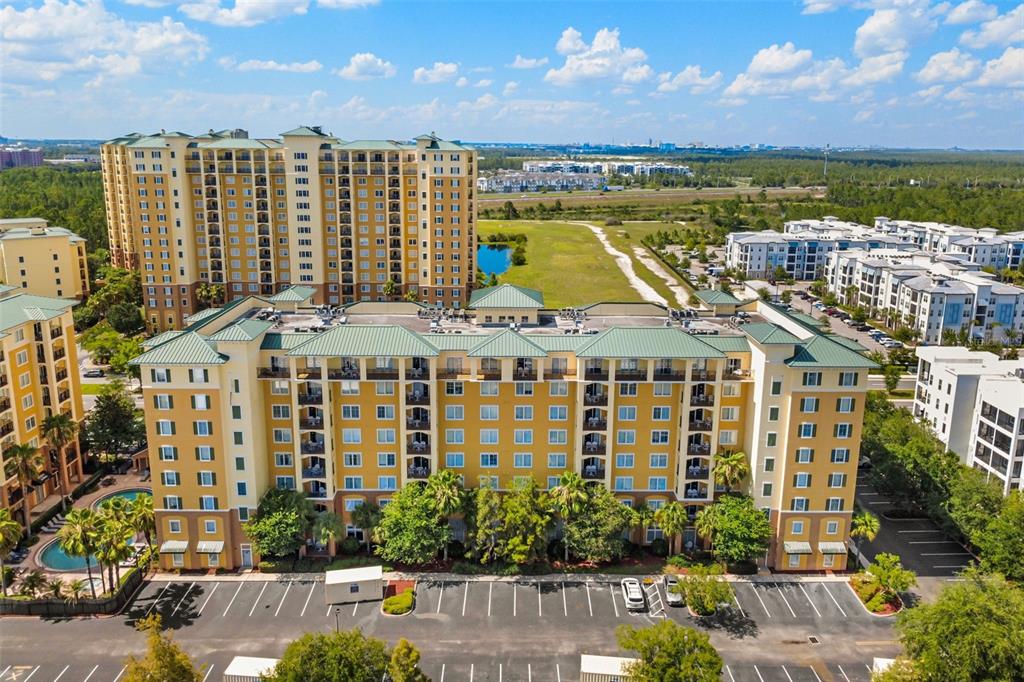 An aerial view shows a large yellow apartment complex with a parking lot below — 8100 POINCIANA BOULEVARD UNIT 2505, ORLANDO, FL