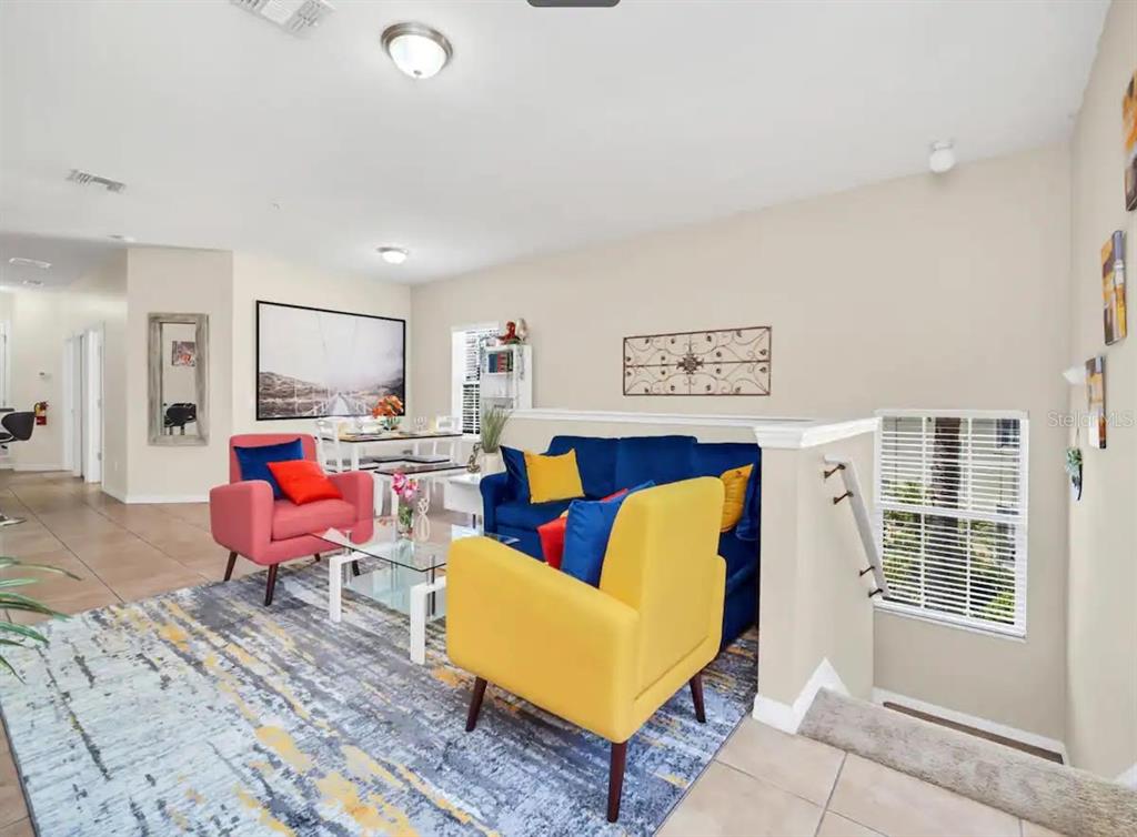 A living room features a blue sofa, yellow and pink armchairs, and a patterned rug — 2736 OAKWATER DRIVE, KISSIMMEE, FL