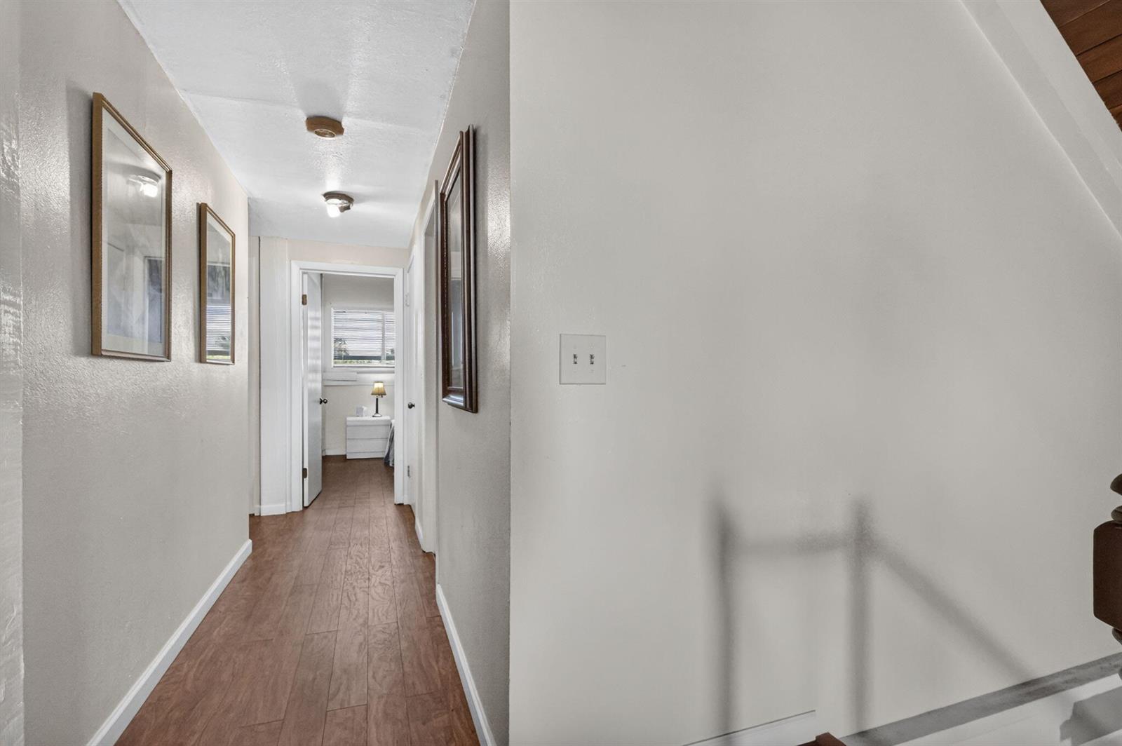 A hallway with wood-look flooring leads to a bedroom featuring a light-colored wall — 6022 Western Way, Lake Worth FL 33463, LAKE WORTH, FL