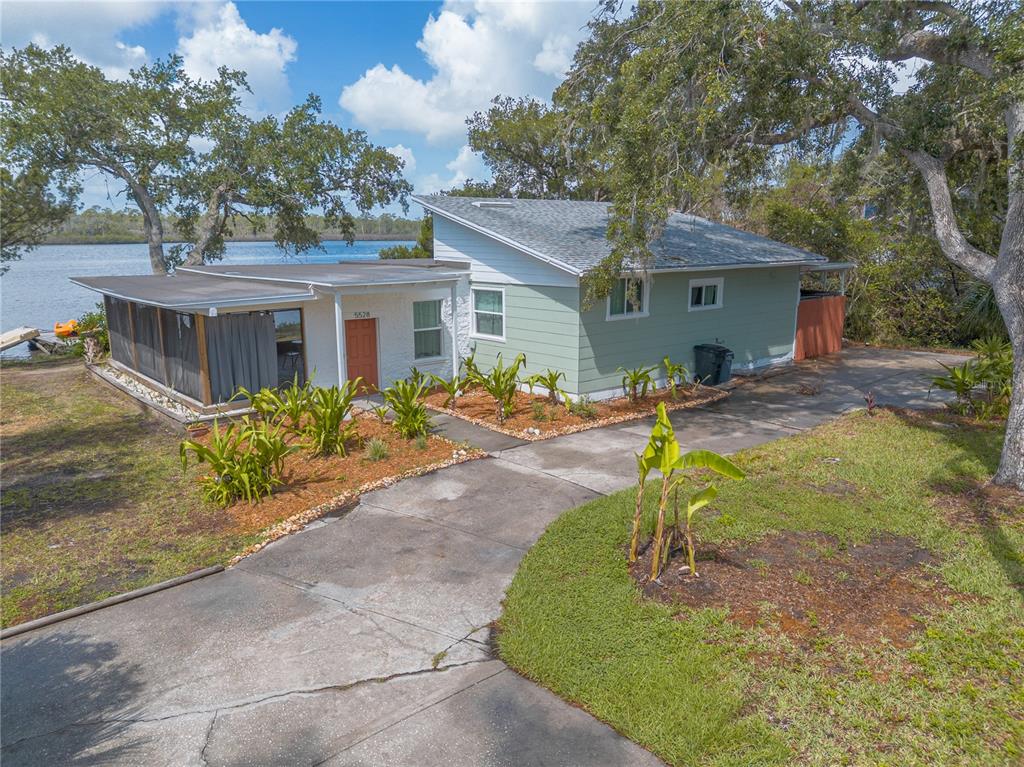 A light green house with a flat-roofed porch sits on a lot near the water — 5528 W BAYSHORE DRIVE, PORT ORANGE, FL