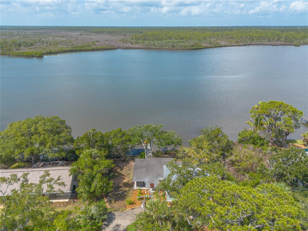 An aerial view shows a house with a dock situated on a waterfront lot — 5528 W BAYSHORE DRIVE, PORT ORANGE, FL