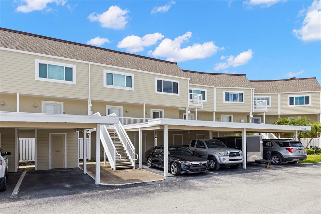 A multi-unit residential building features covered parking spaces and an exterior staircase — 433 S PAULA DRIVE UNIT 28, DUNEDIN, FL