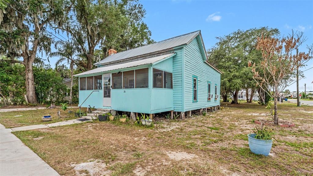 A light blue, elevated wooden house with a screened-in porch sits on a grassy lot — 20 S LANIER AVENUE, FORT MEADE, FL