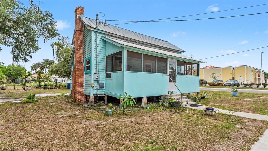 A light blue wooden house with a metal roof and a screened-in front porch — 20 S LANIER AVENUE, FORT MEADE, FL