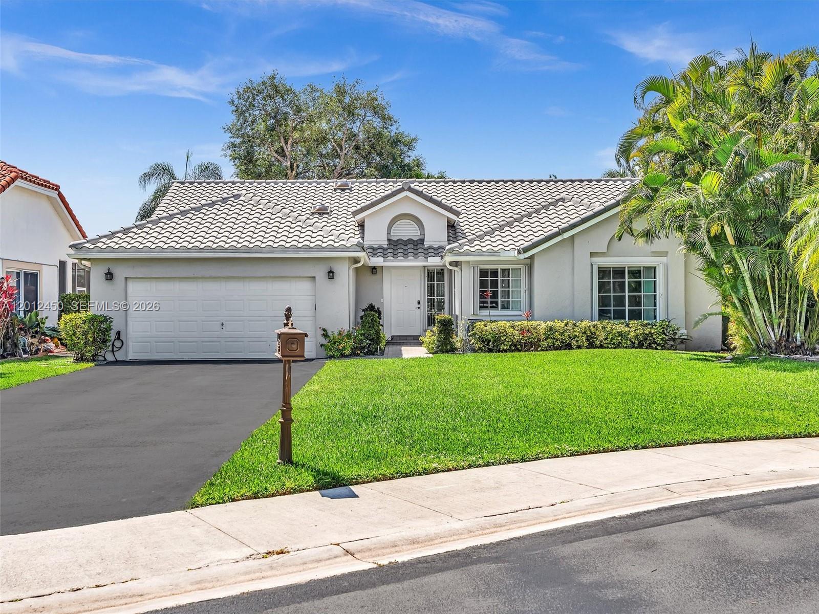 A single-story house with a tiled roof, white exterior, two-car garage, and a front lawn — 629 Spinnaker, Weston FL 33326, WESTON, FL