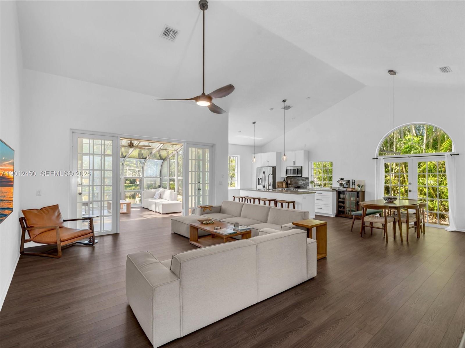 An open-concept living and dining area features vaulted ceilings, wood flooring, and a sunroom — 629 Spinnaker, Weston FL 33326, WESTON, FL