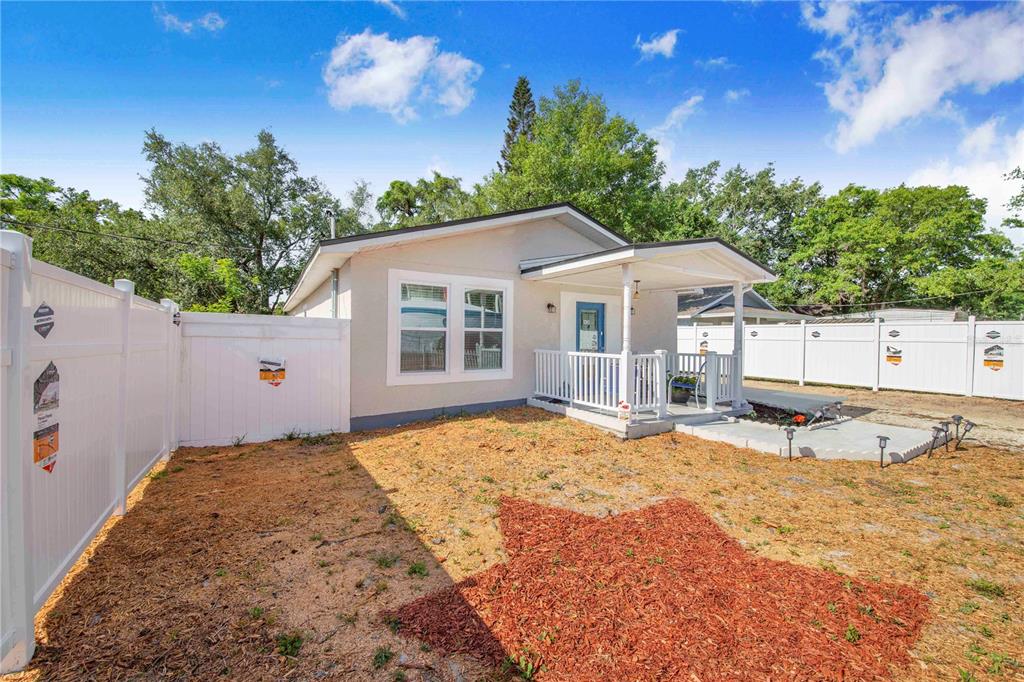 A single-story house with a white vinyl fence, a front porch, and a star-shaped mulch bed — 3420 AVENUE T NW, WINTER HAVEN, FL