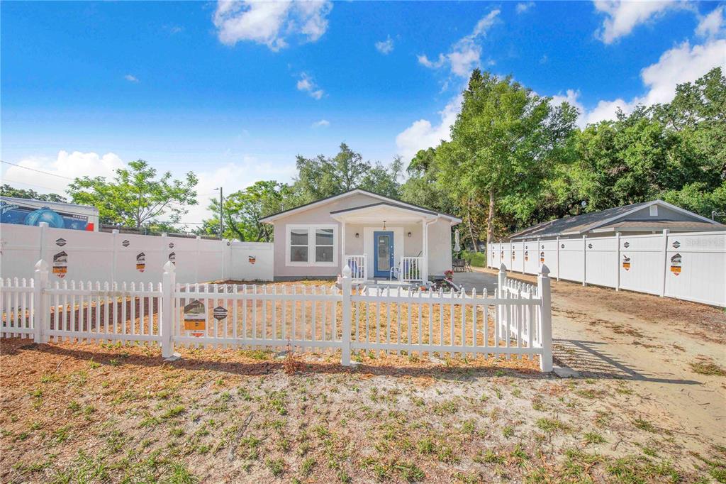 A single-story house with a blue front door sits behind a white picket fence — 3420 AVENUE T NW, WINTER HAVEN, FL