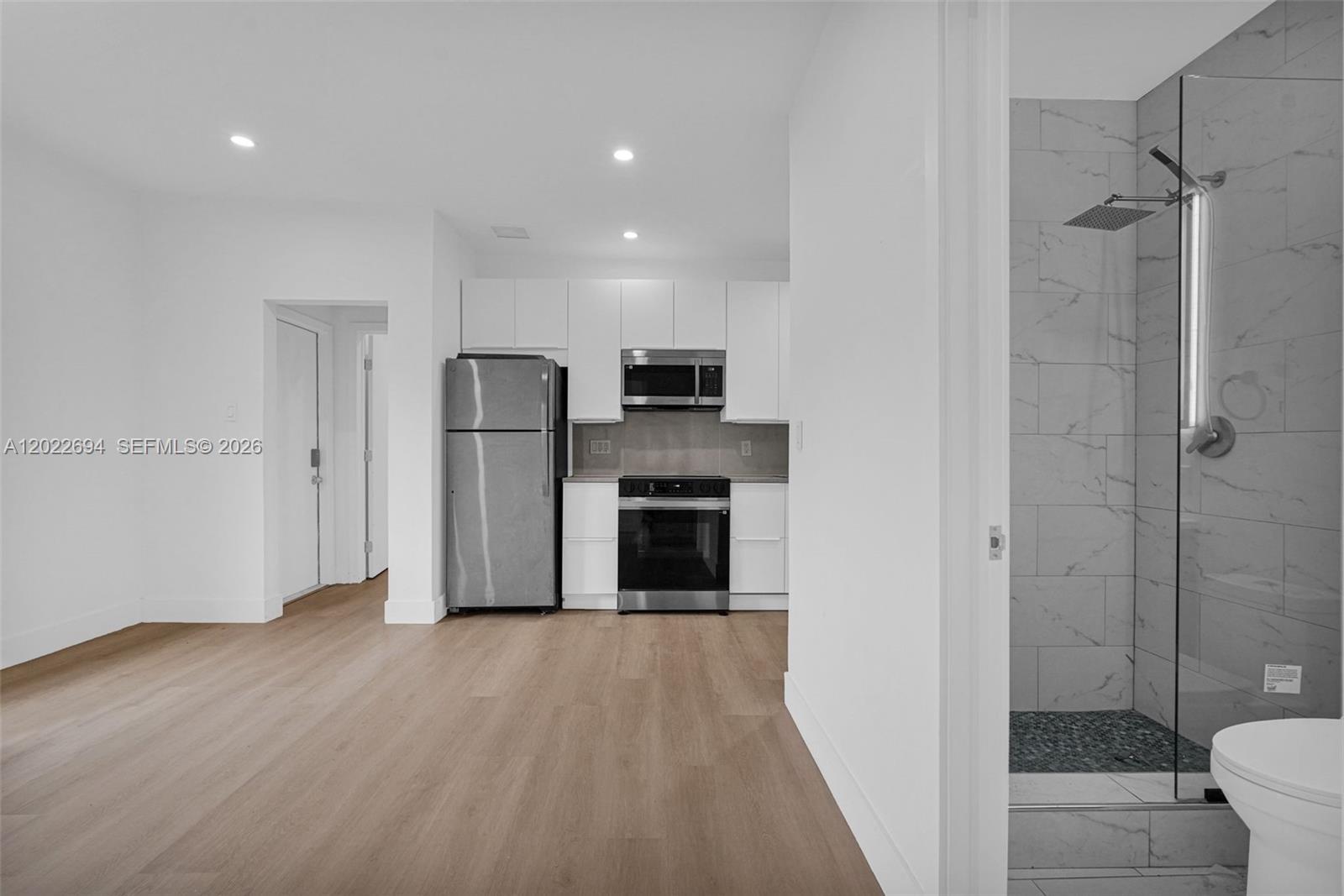 A view of a kitchen with stainless steel appliances and a bathroom with a shower — 19 NE 48th St # 1, Miami FL 33137, MIAMI, FL
