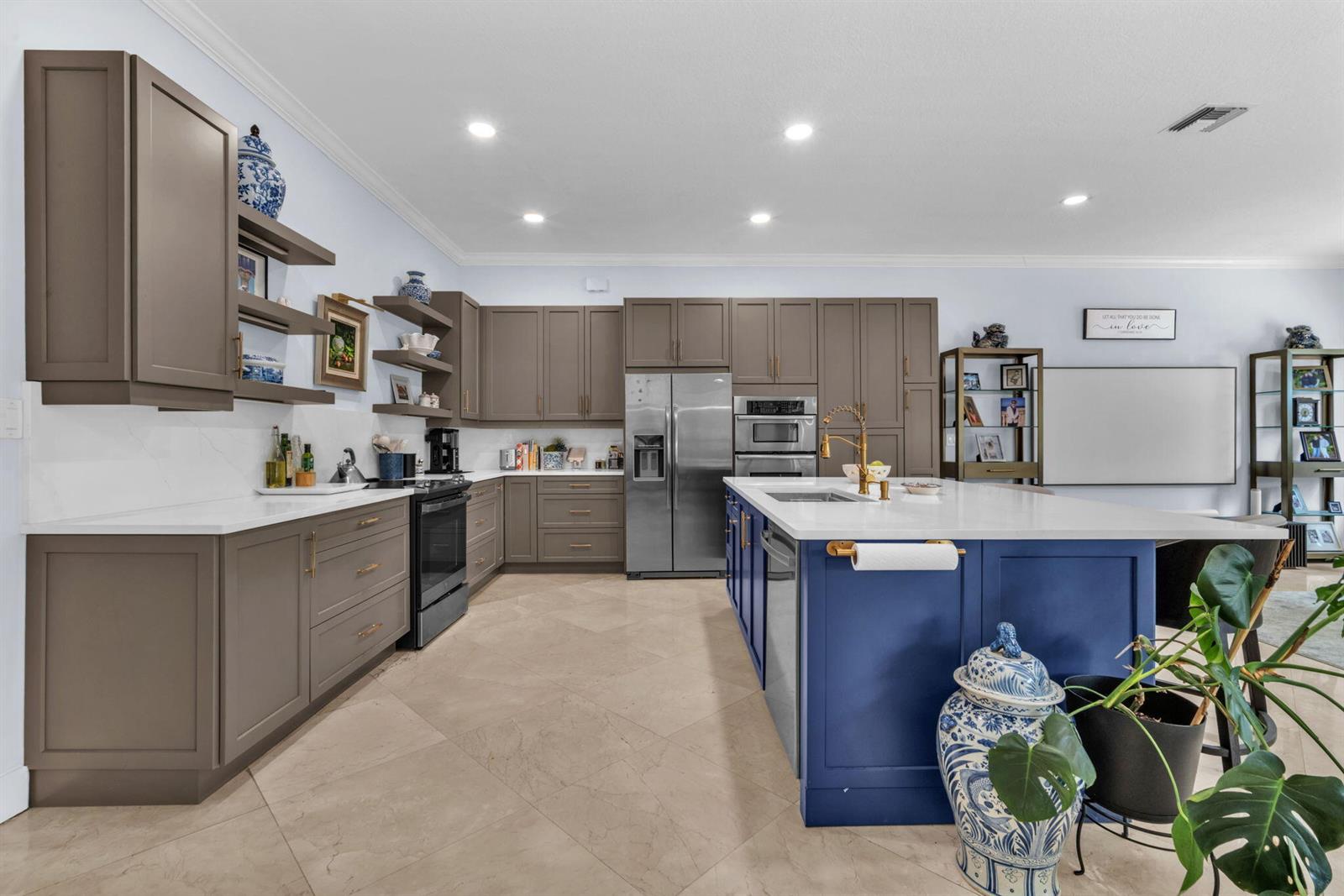 A kitchen features taupe cabinetry, a blue island, white countertops, and stainless steel appliances — 4538 Danielson Drive, Lake Worth FL 33467, LAKE WORTH, FL