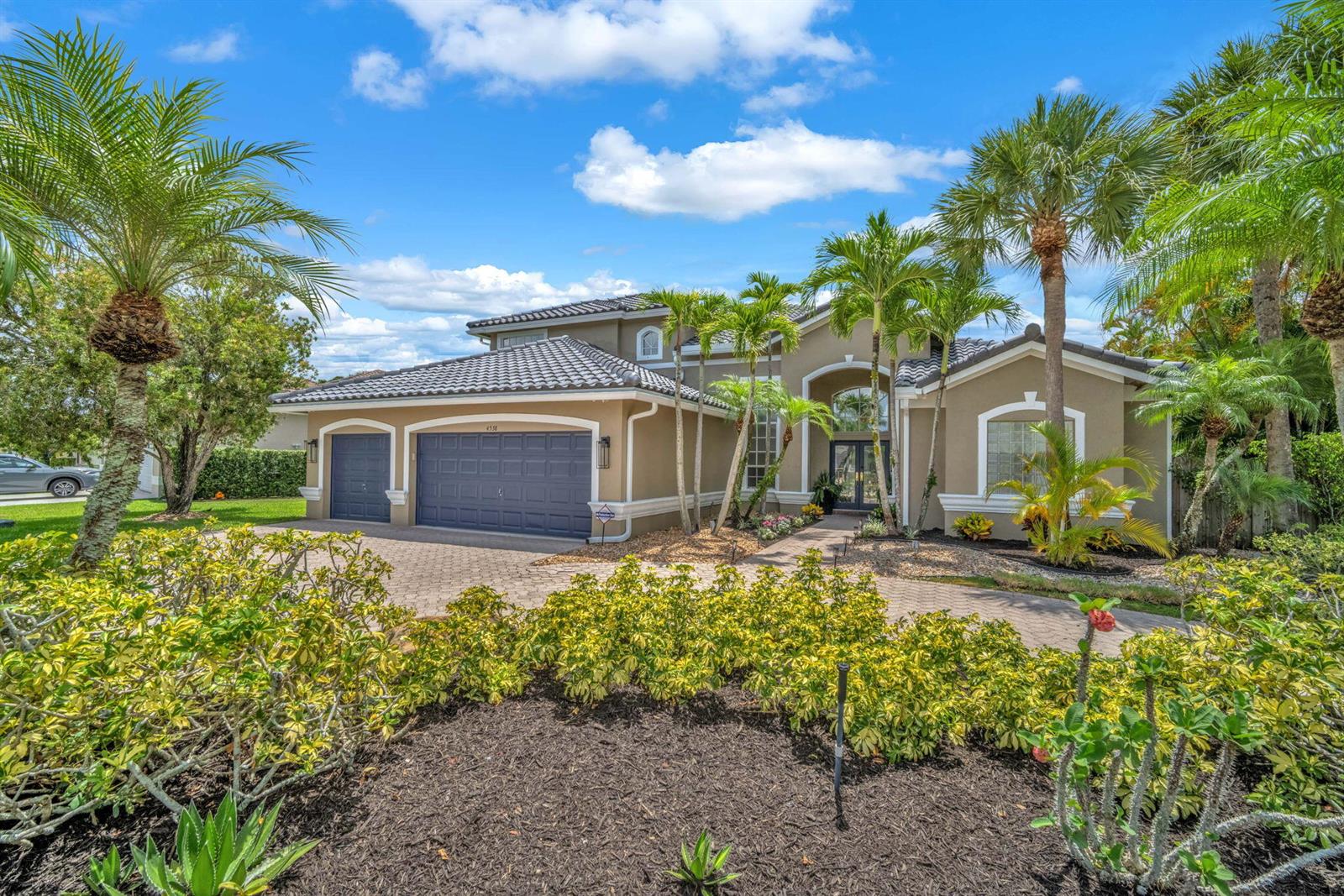 A tan single-story house with a dark blue garage and palm trees in the front yard — 4538 Danielson Drive, Lake Worth FL 33467, LAKE WORTH, FL