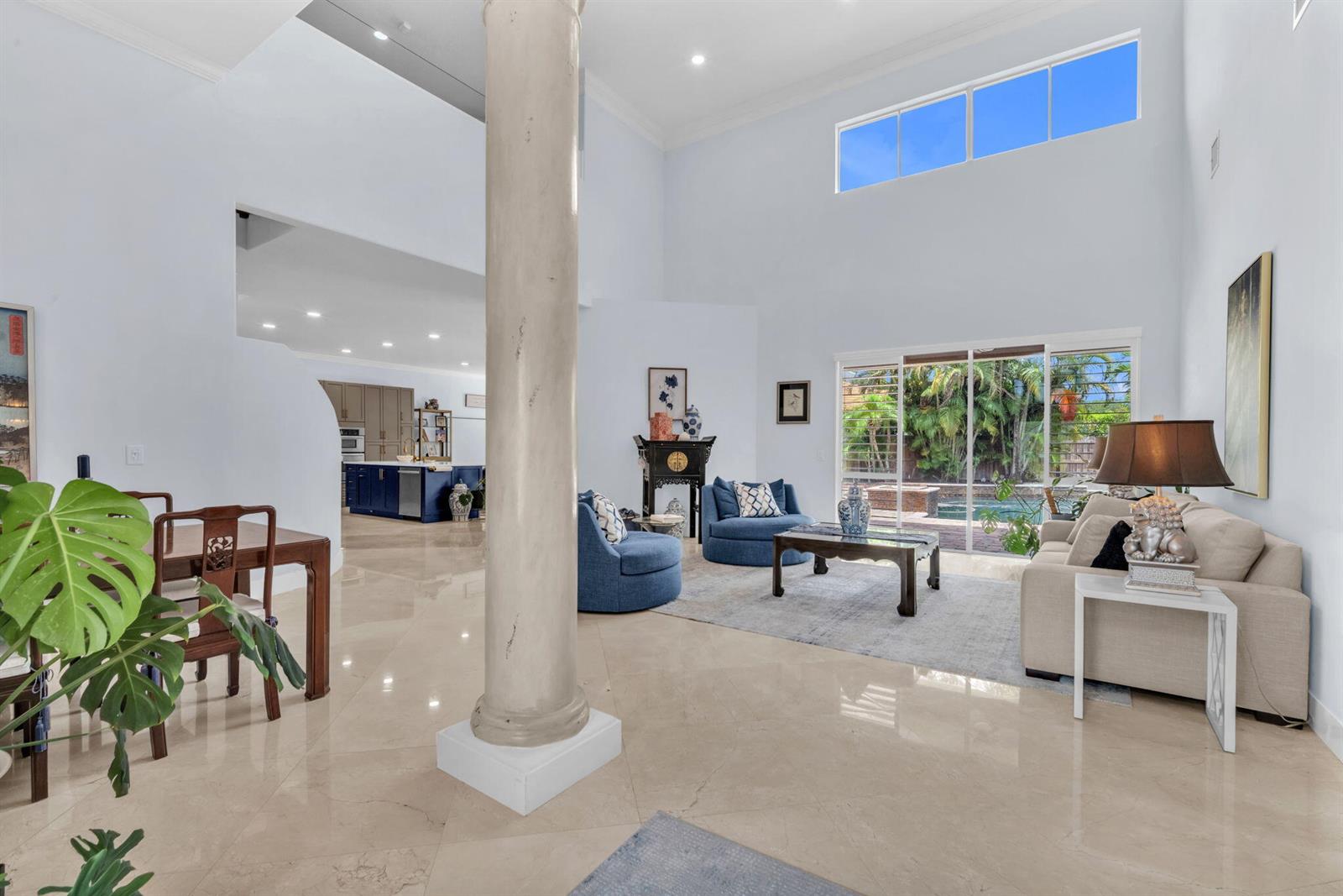 A spacious living room with high ceilings, a central column, and views of a pool — 4538 Danielson Drive, Lake Worth FL 33467, LAKE WORTH, FL