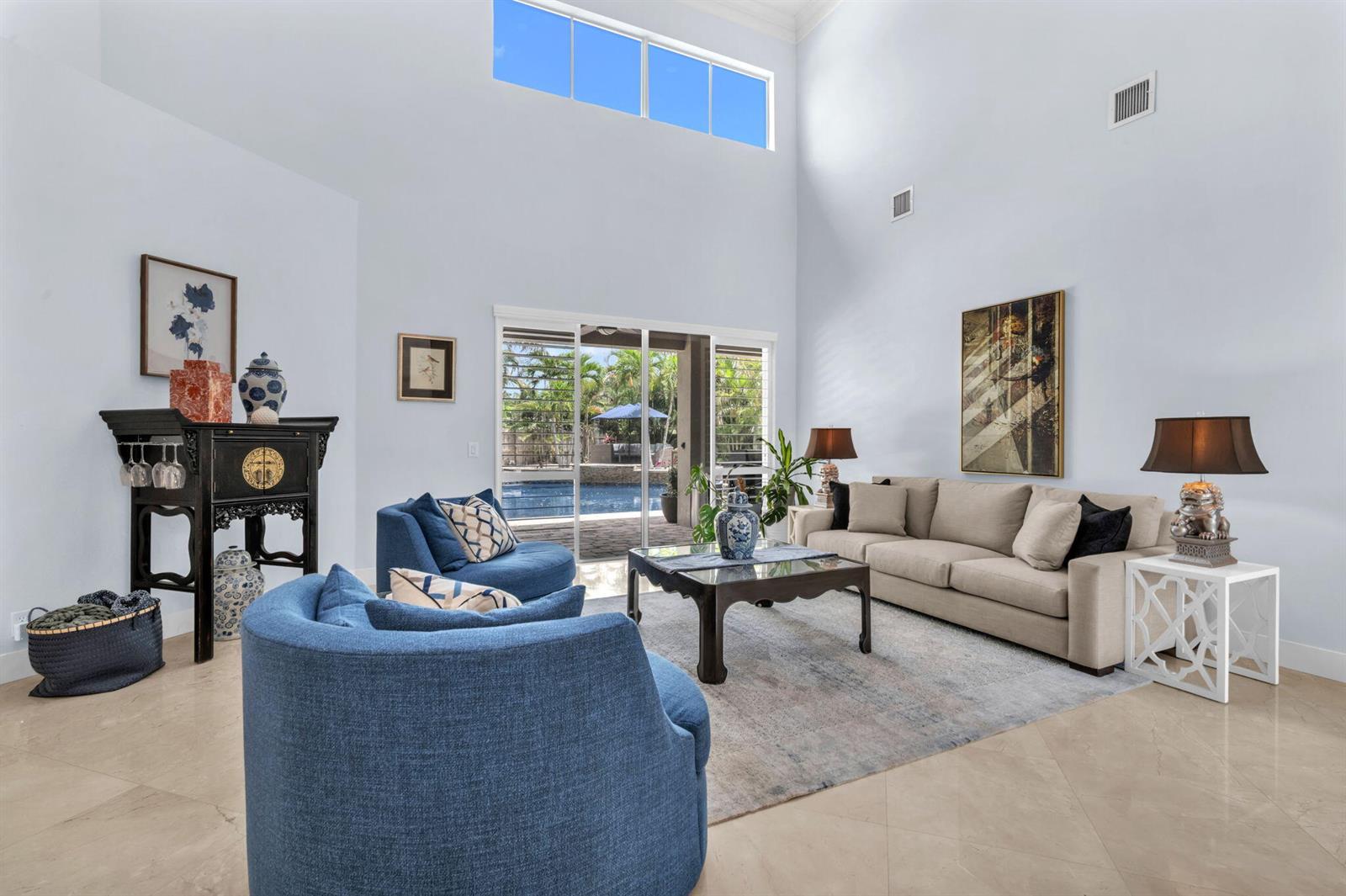 A high-ceilinged living room features blue armchairs, a beige sofa, and sliding glass doors — 4538 Danielson Drive, Lake Worth FL 33467, LAKE WORTH, FL