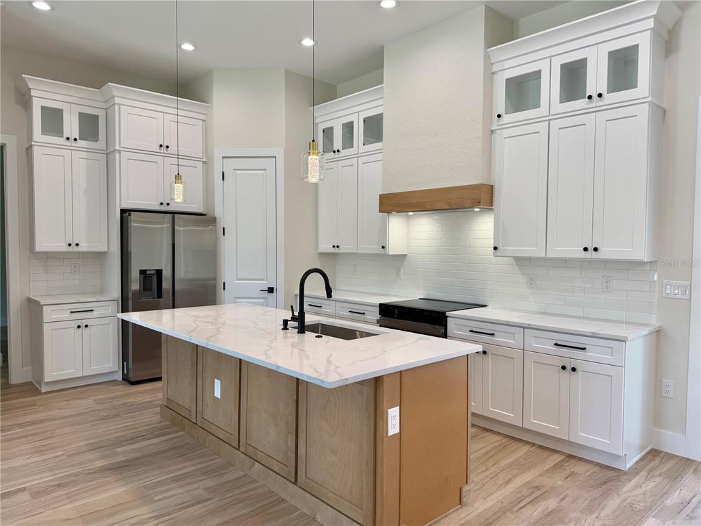 A kitchen features white cabinetry, a wood-toned island, stainless steel appliances, and quartz countertops — 3739 GARBETT TERRACE, NORTH PORT, FL