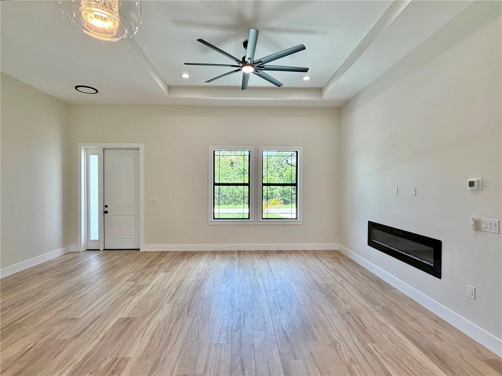 A living room features light wood flooring, a tray ceiling with a fan, and a fireplace — 3739 GARBETT TERRACE, NORTH PORT, FL