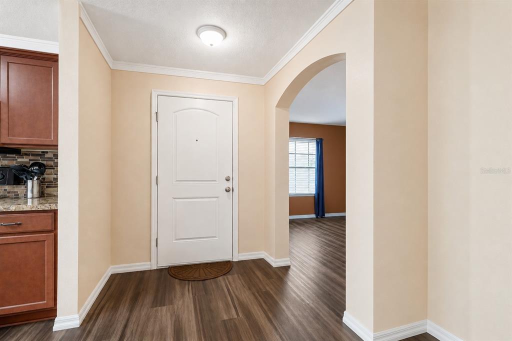 An entryway with a white door, wood-look flooring, and an arched doorway leading to another room — 2665 ROTHERHAM ROAD, TAVARES, FL