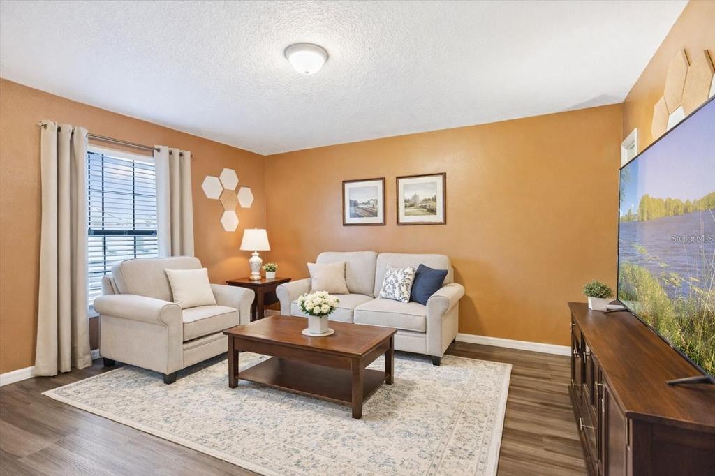 A living room features tan walls, light-colored furniture, a wooden coffee table, and wood flooring — 2665 ROTHERHAM ROAD, TAVARES, FL