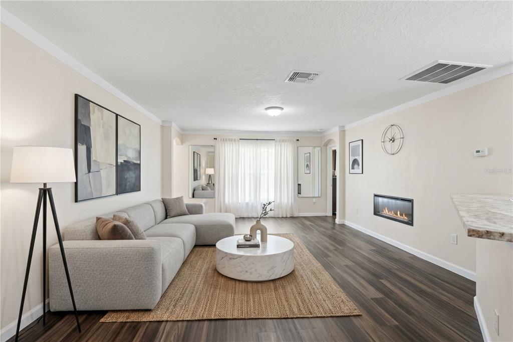 A living room features a grey sectional sofa, a round coffee table, and a wall fireplace — 2665 ROTHERHAM ROAD, TAVARES, FL