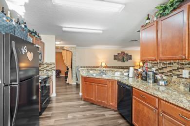 A kitchen features wood cabinets, granite countertops, stainless steel appliances, and wood-look flooring — 2665 ROTHERHAM ROAD, TAVARES, FL