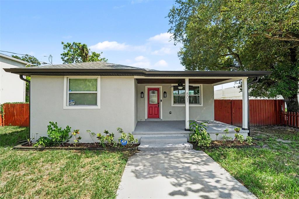 A single-story house with a light-colored exterior, a red front door, and a covered porch — 801 E BAKER STREET, TAMPA, FL