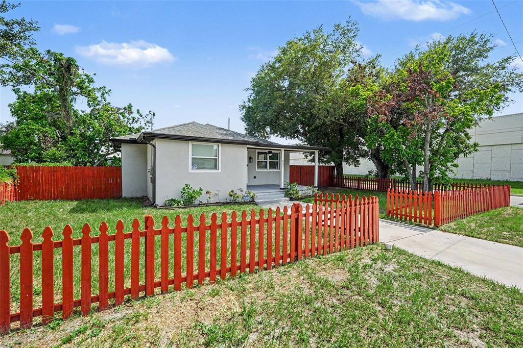A single-story house with light-colored siding and a red picket fence in the yard — 801 E BAKER STREET, TAMPA, FL