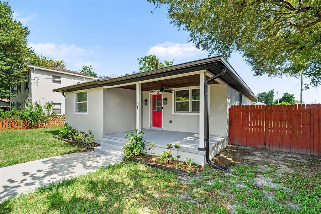 A single-story house with a red front door, covered porch, and red wooden fence — 801 E BAKER STREET, TAMPA, FL