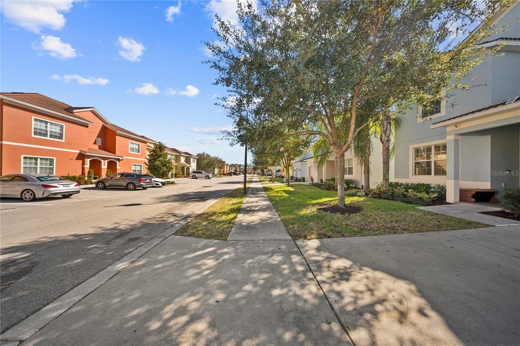 A sidewalk leads through a residential neighborhood with parked cars and multi-story apartment buildings — 8960 BISMARCK PALM RD, KISSIMMEE, FL