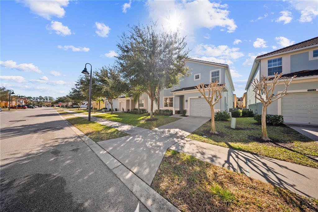 A light blue two-story house with a garage and sidewalk on a sunny day — 8960 BISMARCK PALM RD, KISSIMMEE, FL