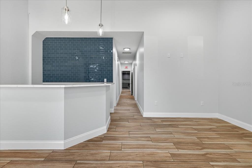 A room with wood-look tile flooring, a white counter, and a blue tiled accent wall — 10 FLORIDA PARK DRIVE UNIT C, PALM COAST, FL