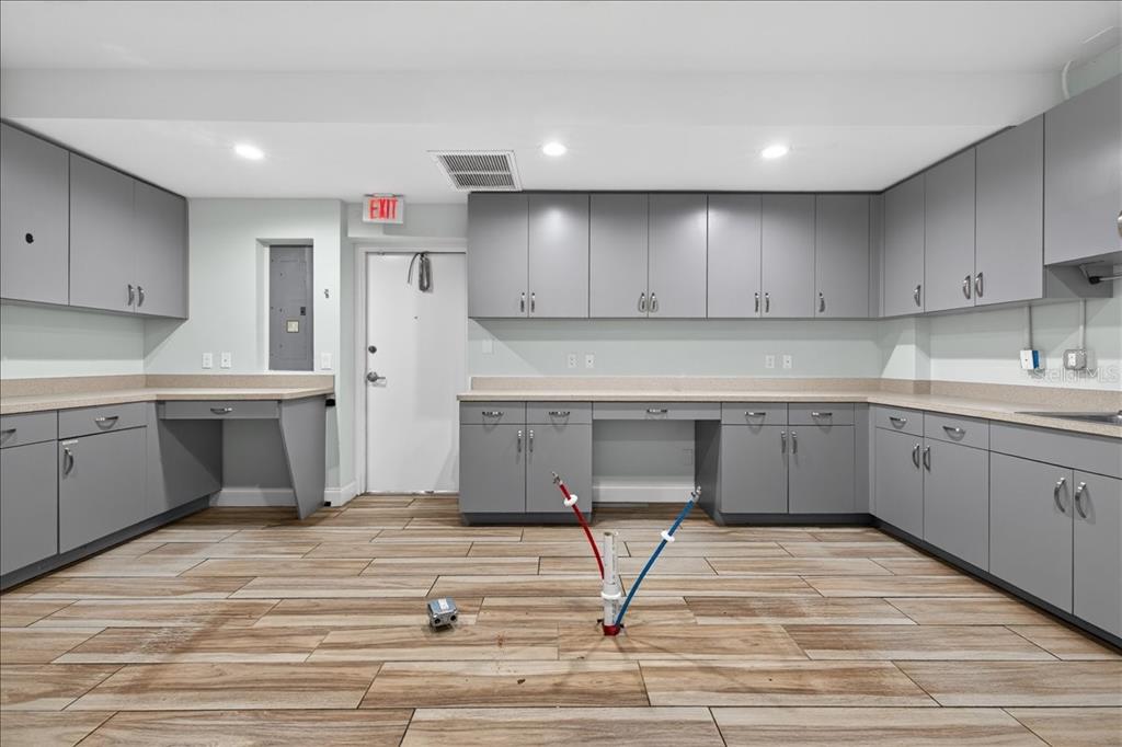 A room with gray cabinets, light countertops, wood-look tile flooring, and exposed plumbing pipes — 10 FLORIDA PARK DRIVE UNIT C, PALM COAST, FL