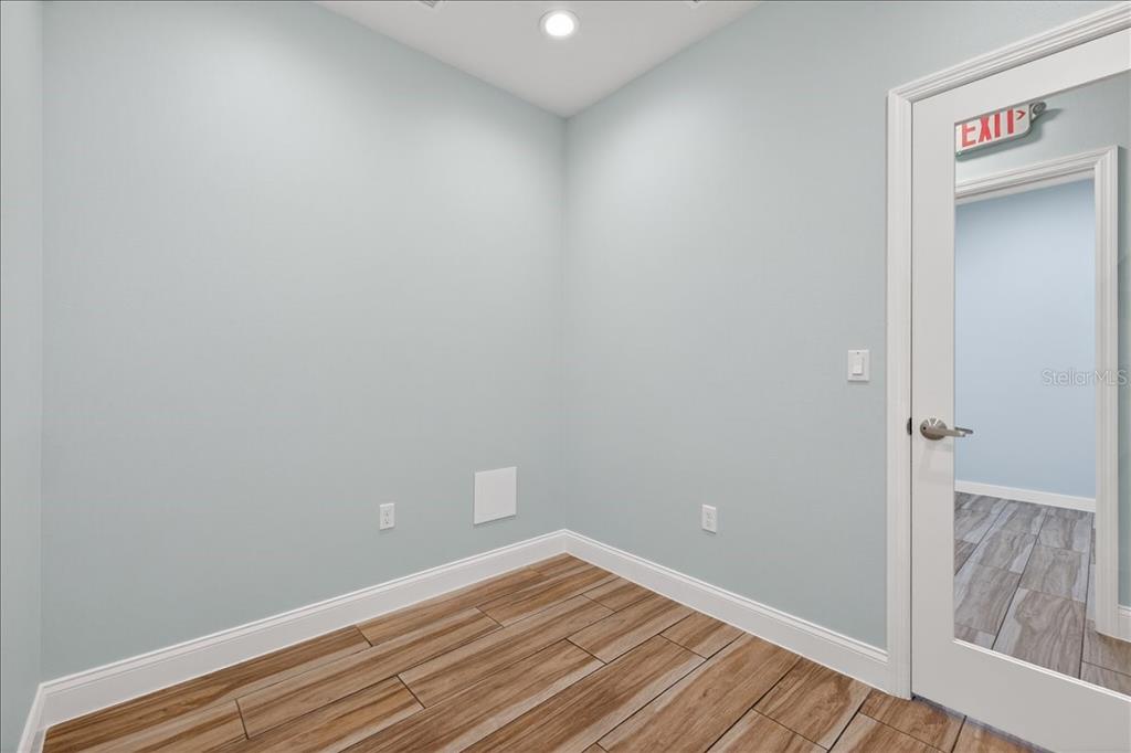 A small room with light blue walls, wood-look tile flooring, and a glass-paneled door — 10 FLORIDA PARK DRIVE UNIT C, PALM COAST, FL