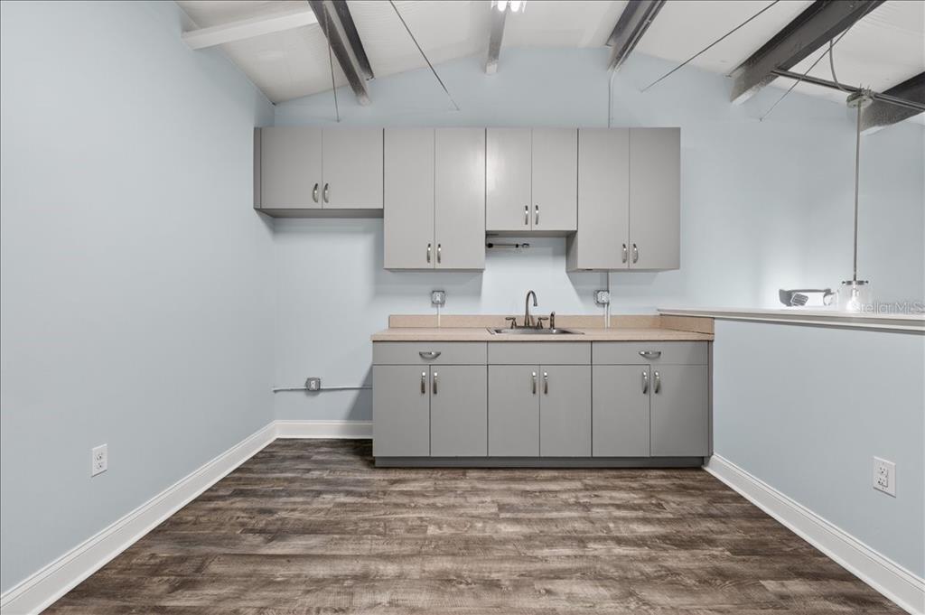 A laundry room with gray cabinets, a sink, and wood-look flooring under a vaulted ceiling — 10 FLORIDA PARK DRIVE UNIT C, PALM COAST, FL