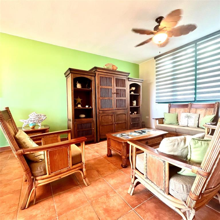 A living room features rattan furniture, a wooden entertainment center, and a bright green wall — 22-01 COND. RIO MAR VILLAGE UNIT #22-01, RIO GRANDE, PR