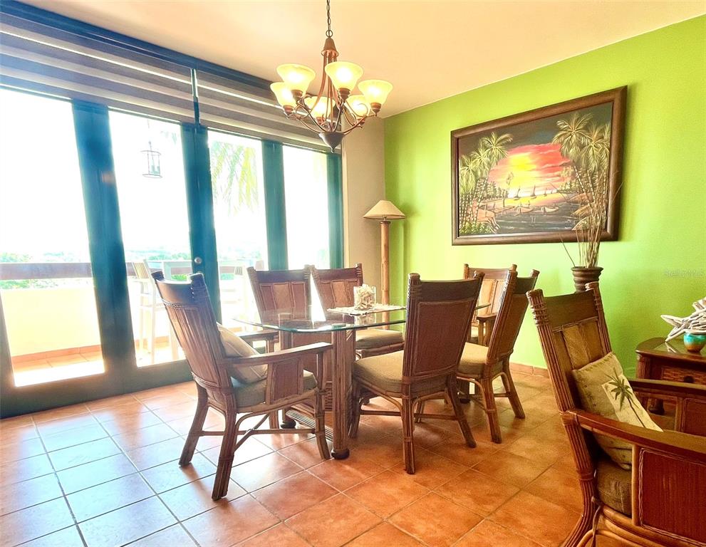 A dining room with a glass table, wicker chairs, tile floors, and a green wall — 22-01 COND. RIO MAR VILLAGE UNIT #22-01, RIO GRANDE, PR