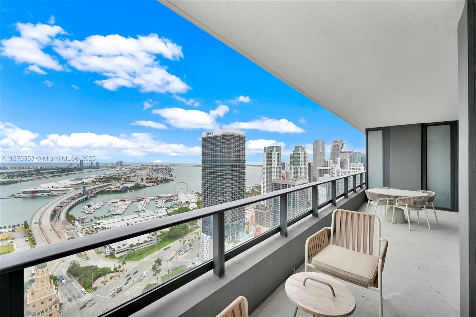 A high-rise balcony overlooks a city skyline, a marina, and a bridge over the water — 159 NE 6th St # 4015, Miami FL 33132, MIAMI, FL