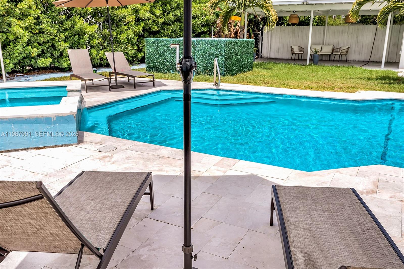 A backyard swimming pool with a hot tub and lounge chairs on a stone patio — 703 NE 7th St # 5, Hallandale Beach FL 33009, HALLANDALE BEACH, FL