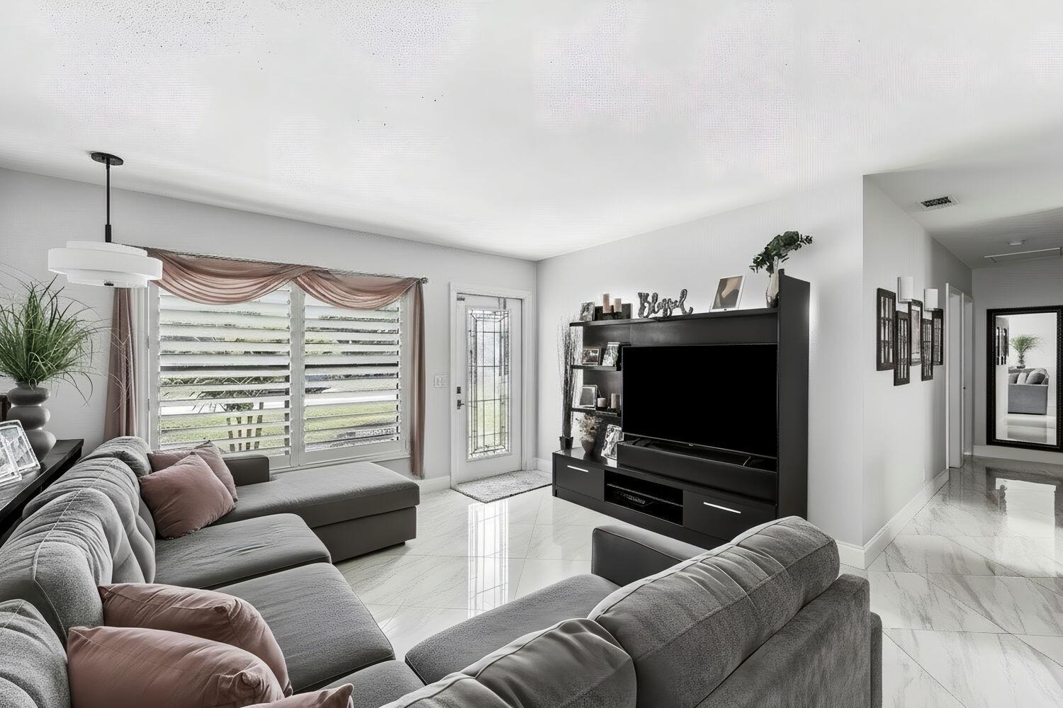 A living room features a large grey sectional sofa, pink pillows, and white marble flooring — 517 Ibis Drive, Delray Beach FL 33444, DELRAY BEACH, FL