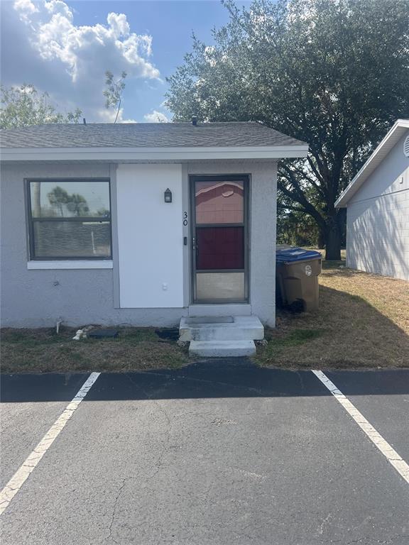The exterior of a single-story gray building features a front door, window, and parking space — 30 LAKE VILLA WAY, KISSIMMEE, FL