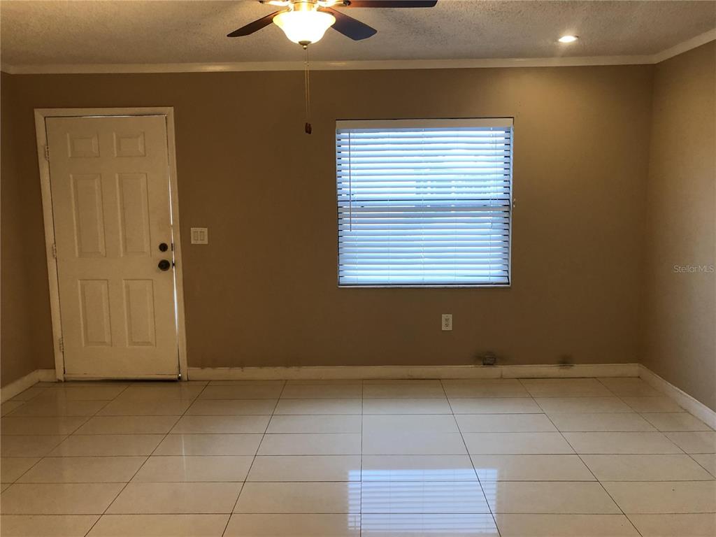 A room with light-colored tile flooring, a white door, and a window with blinds — 30 LAKE VILLA WAY, KISSIMMEE, FL