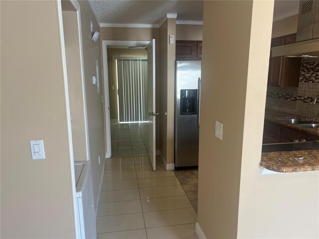 A hallway with tile flooring leads to a doorway with vertical blinds — 30 LAKE VILLA WAY, KISSIMMEE, FL