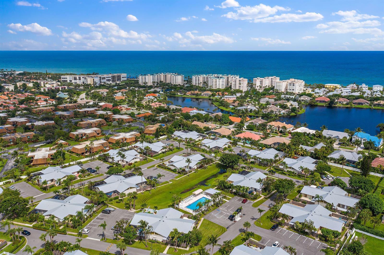 An aerial view shows a residential community with houses, a swimming pool, and nearby oceanfront buildings — 1801 S Us Highway 1 # 13a, Jupiter FL 33477, JUPITER, FL