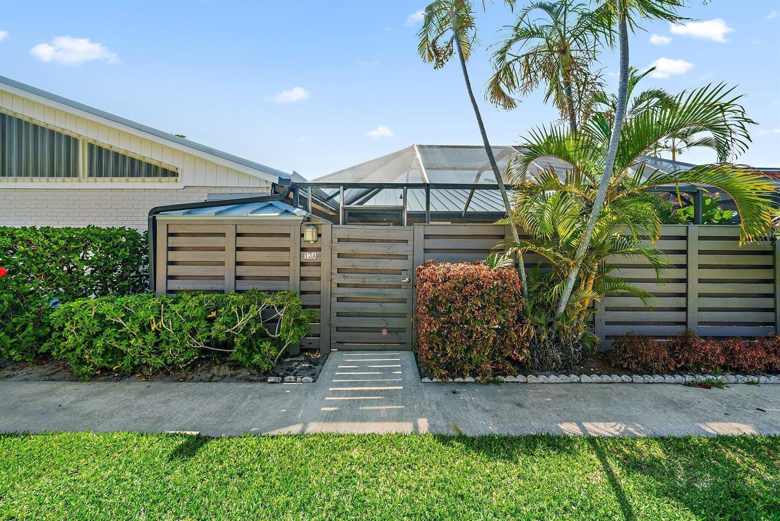 A gated entrance with a wooden fence and walkway leads to a screened patio area — 1801 S Us Highway 1 # 13a, Jupiter FL 33477, JUPITER, FL