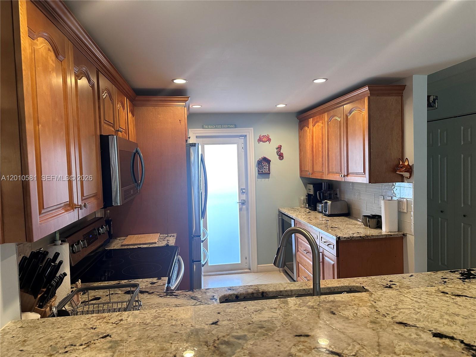 A kitchen features wood cabinets, granite countertops, and stainless steel appliances — 750 N Ocean Blvd # 310, Pompano Beach FL 33062, POMPANO BEACH, FL